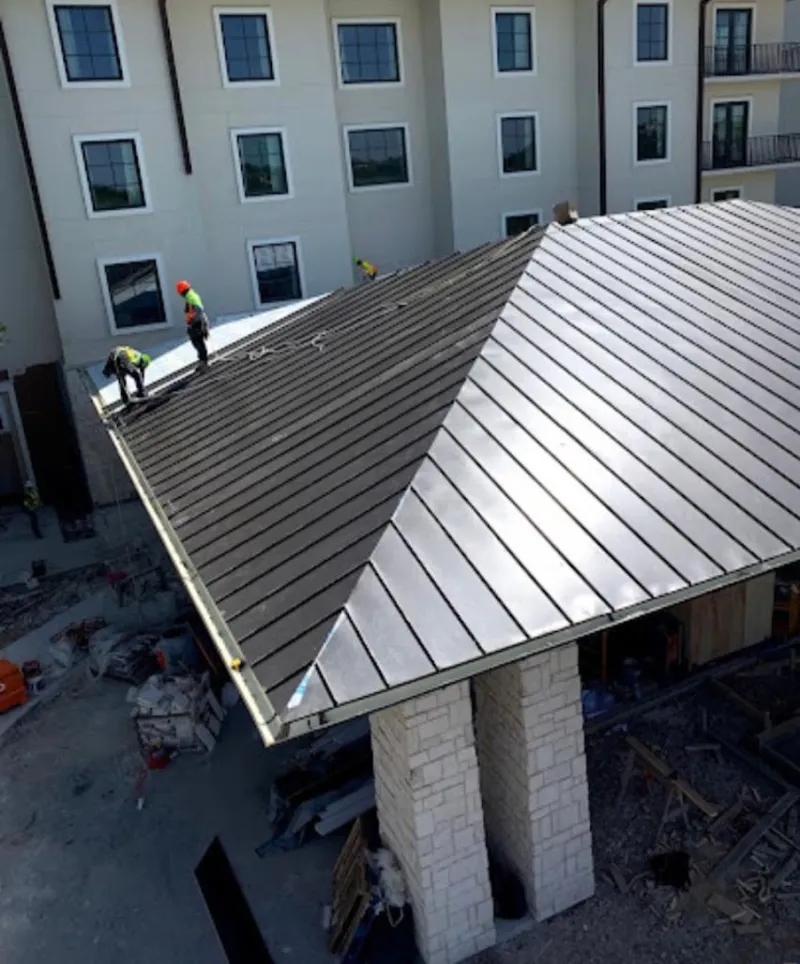 Crew installing standing seam metal roof panels on a commercial project in Groesbeck